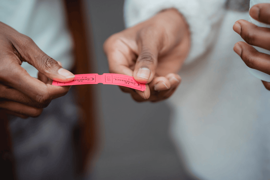 Close up photo of two hands holding two red tickets